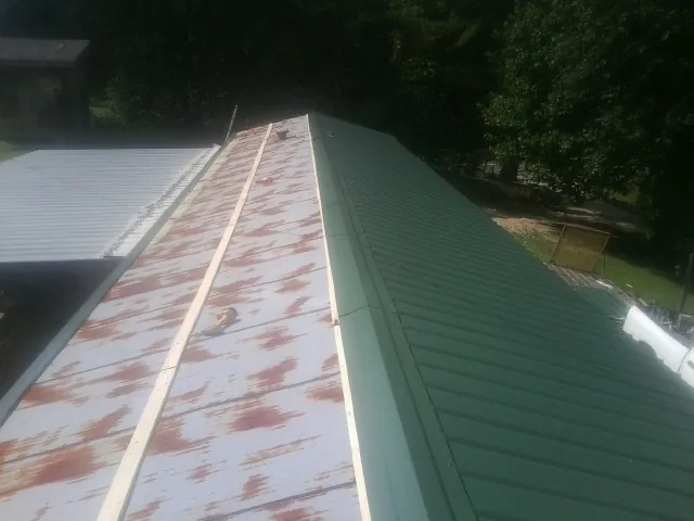 Old rusted panels beside newly installed green metal roofing — Wind Damage Roof Repair by Roofing Brothers in Cranford