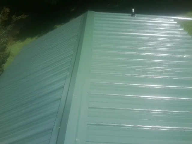 New green metal panels meeting at the ridge of a roof — Flat Roof Repair work by our crew in Cranford