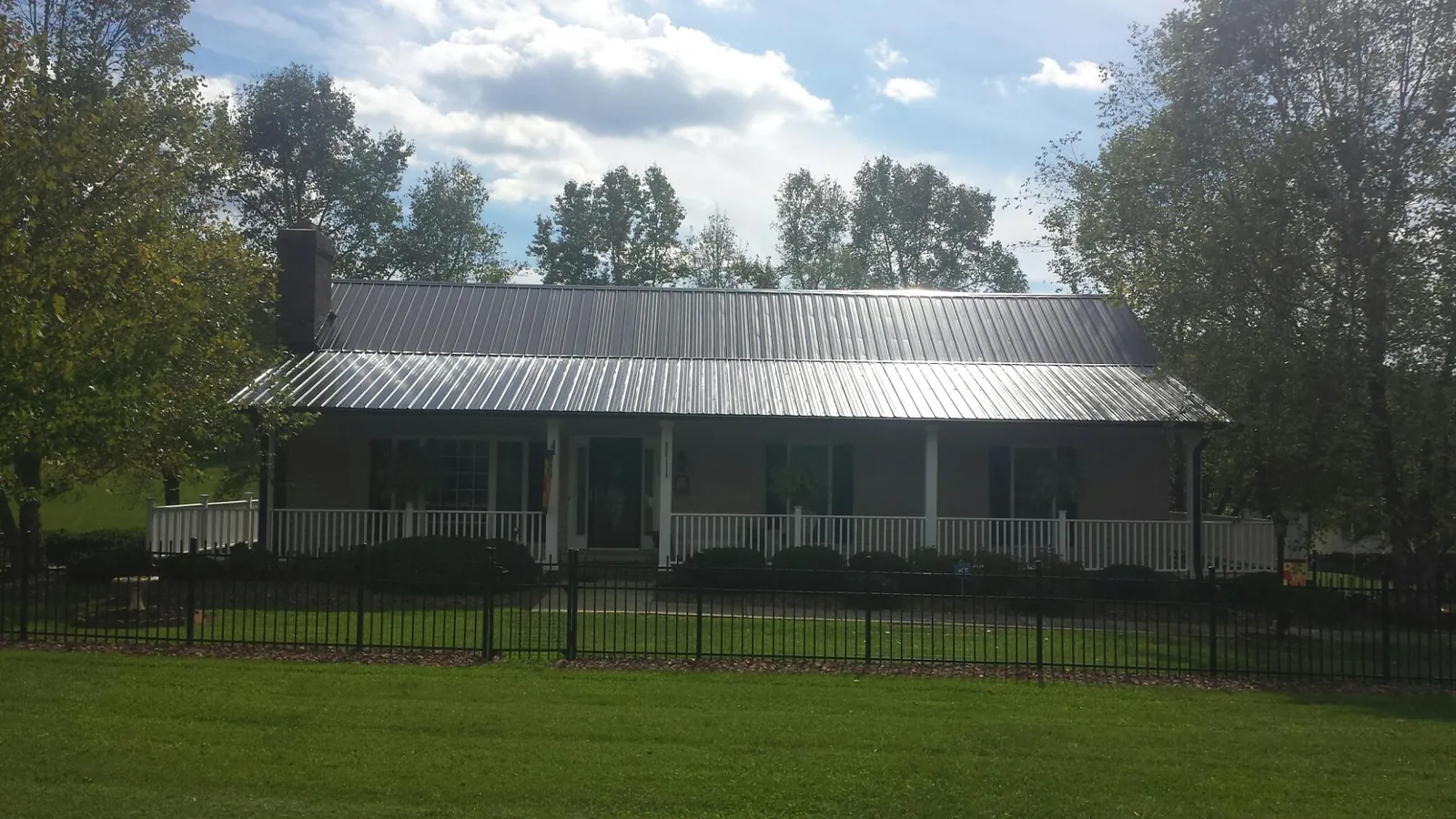 Gray metal roof on a brick ranch with a full width front porch — Gutter Guard Installation work by our crew in Cranford