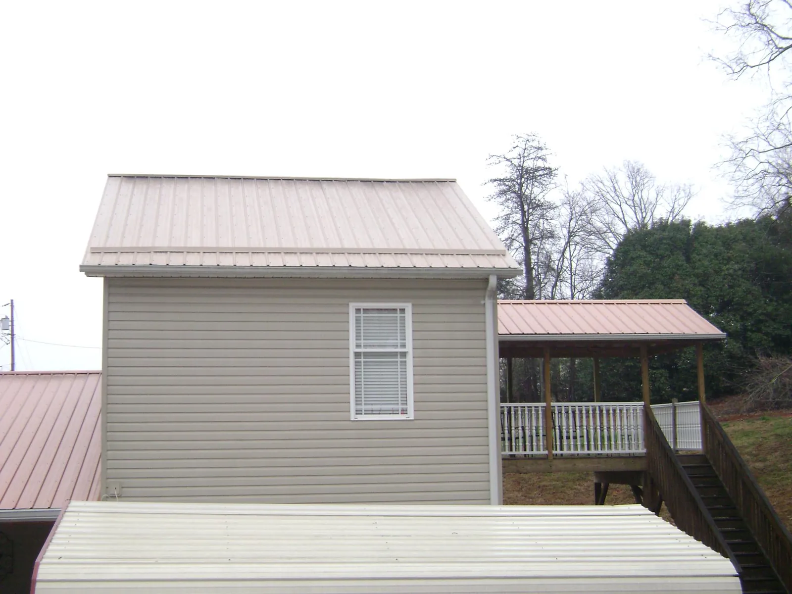 Tan metal roofs on a two story addition and attached porch in Cranford