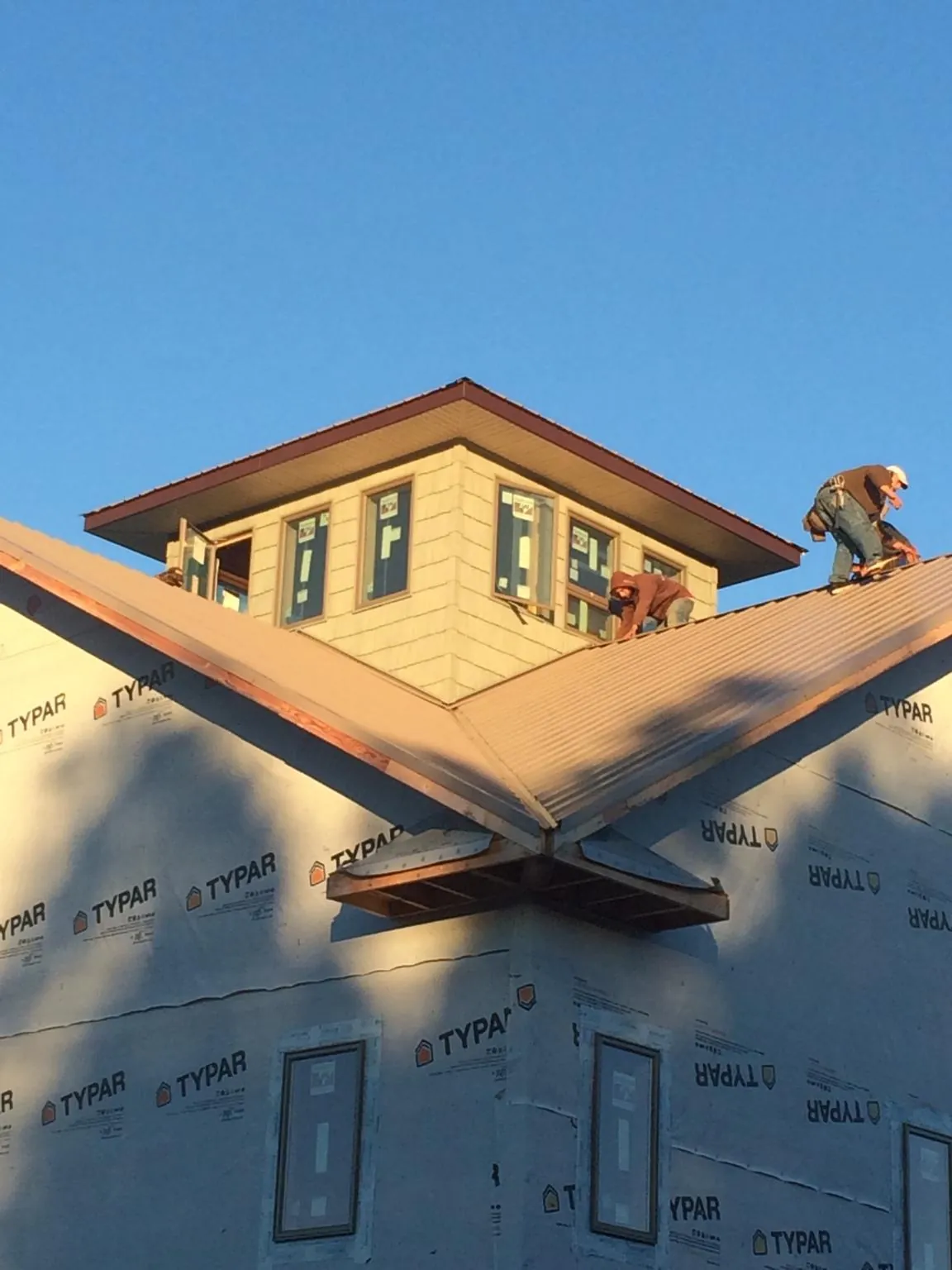 Roofers working around a rooftop cupola on a new metal roof at sunset — Roof Waterproofing in Cranford by Roofing Brothers